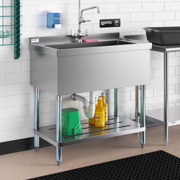 A Regency stainless steel utility sink with a sink shelf underneath.