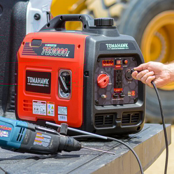 A hand plugging a black power cord into the Tomahawk Inverter Series portable power generator.