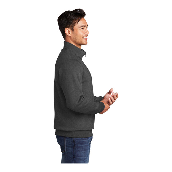 A man wearing a dark heather grey Port & Company 1/4 zip fleece pullover.