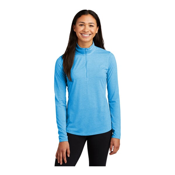 A woman wearing a Sport-Tek Pond Blue Heather quarter-zip pullover sweatshirt.