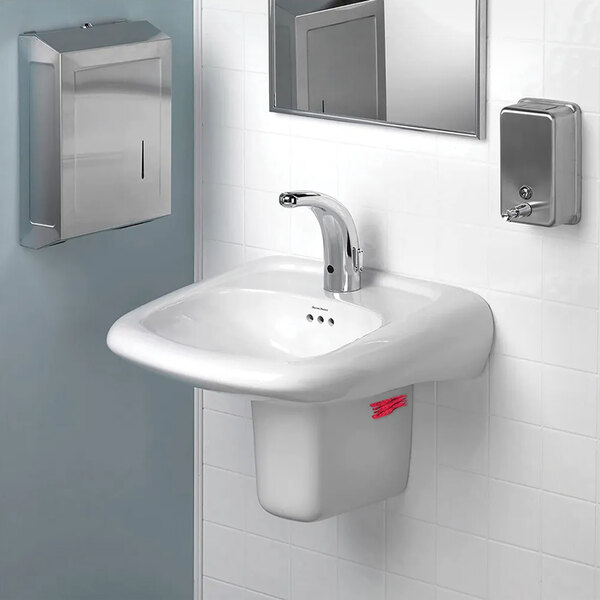 A white bathroom sink with a silver faucet and a WizKid Kiwi Guava Current air freshener on the counter.