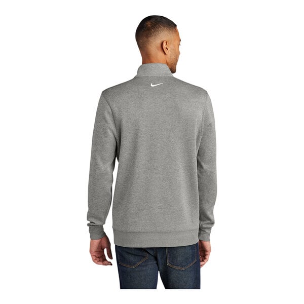 A man wearing a grey Nike Dri-FIT half-zip sweater with a white swoosh on the back.