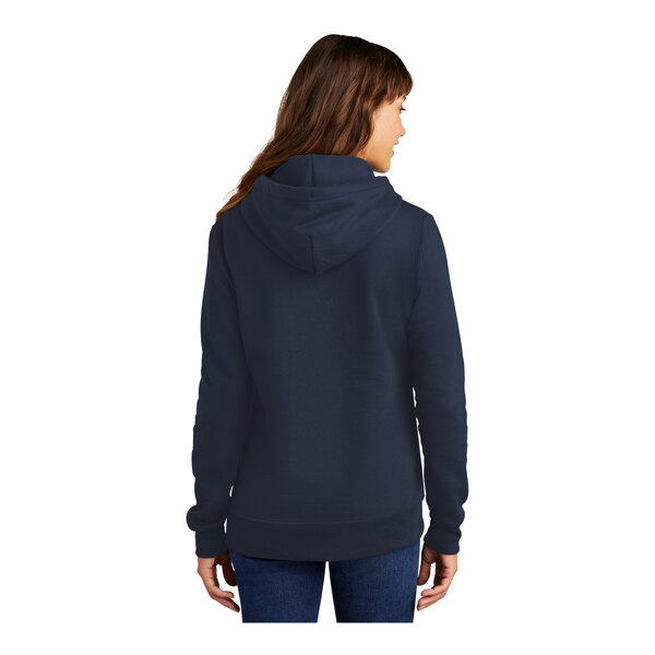 A woman wearing a navy Port & Company Core Fleece pullover hoodie with a hood.