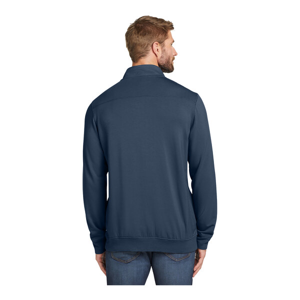 A man wearing a TravisMathew navy blue fleece quarter-zip pullover over a long sleeved shirt.