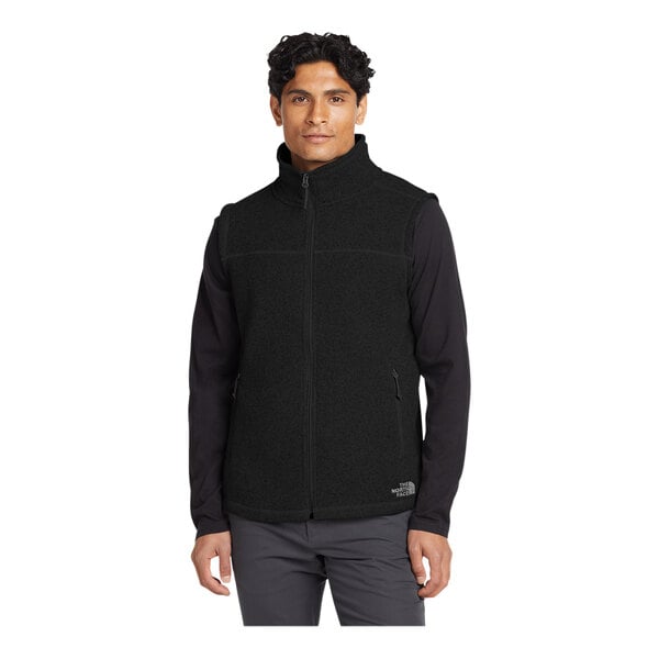 A man wearing a black The North Face fleece vest.