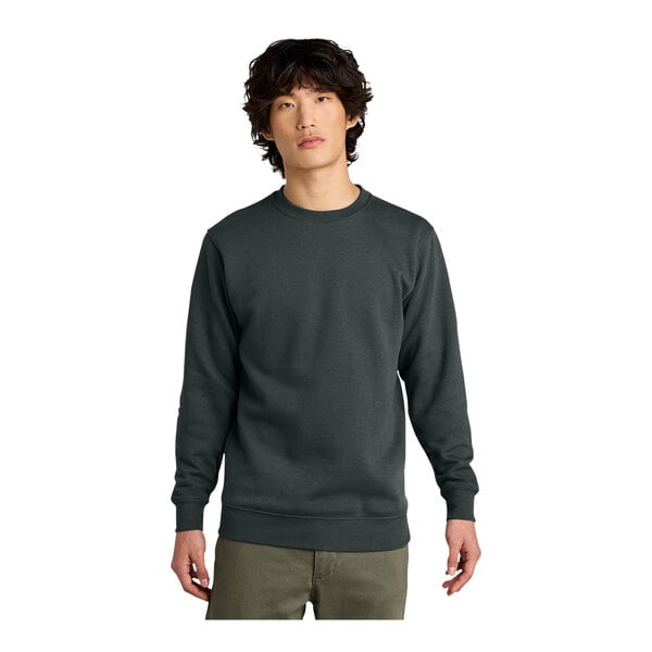 A man wearing a charcoal District V.I.T. crewneck sweatshirt over a long-sleeved shirt.