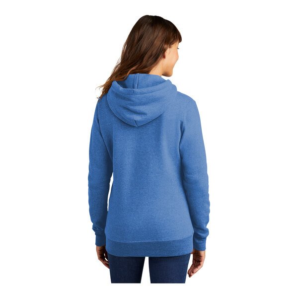 A woman wearing a Port & Company heather royal blue fleece pullover hoodie.
