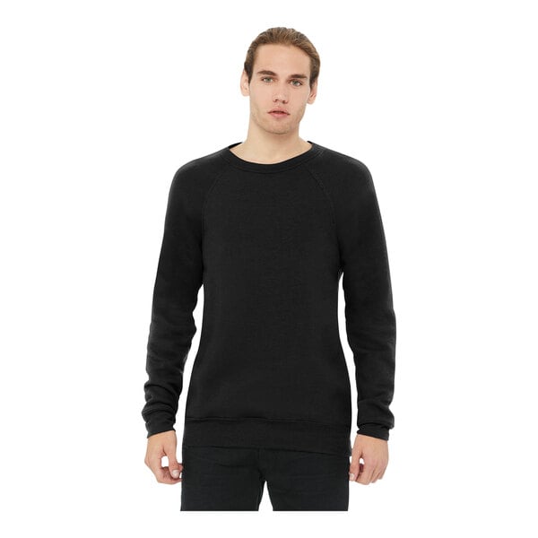 A man wearing a black Bella + Canvas Sponge Fleece Raglan Sweatshirt.