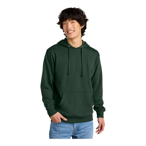 A man wearing a forest green District sweatshirt with a hood.