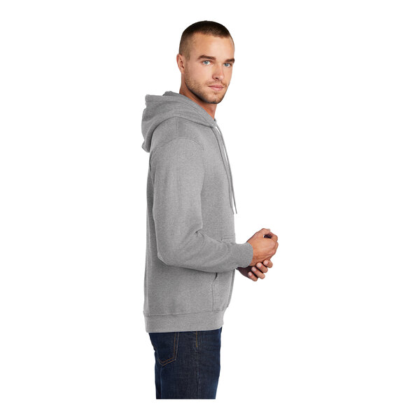 A man wearing a Port & Company athletic heather grey core fleece pullover hoodie.
