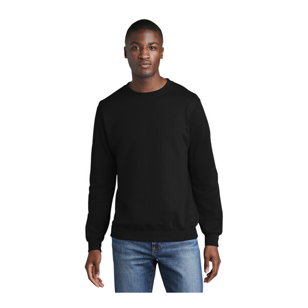A man wearing a black Port & Company core fleece crewneck sweatshirt.