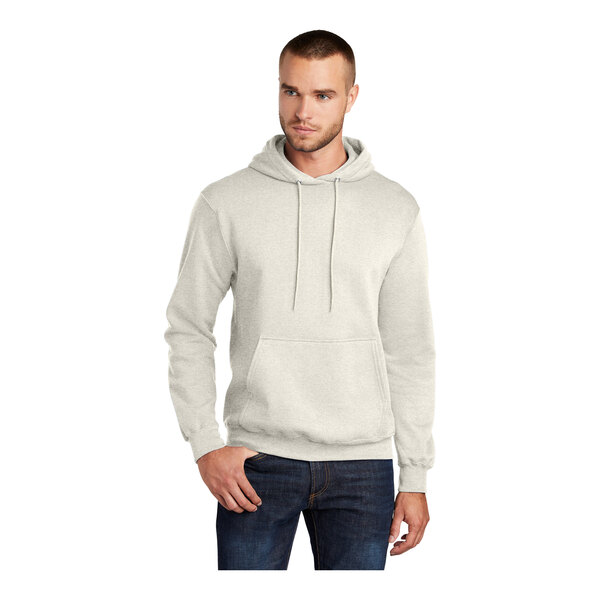 A man wearing an oatmeal heather Port & Company Core Fleece pullover hoodie sweatshirt.