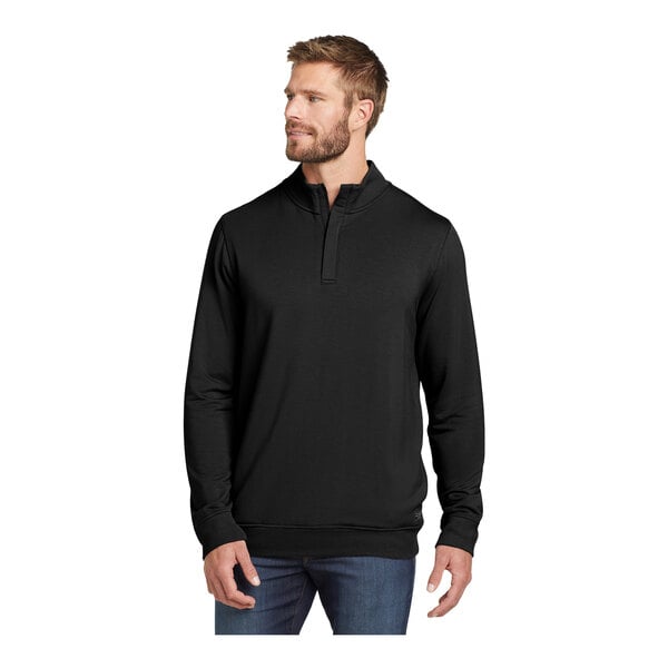 A man wearing a TravisMathew black fleece quarter-zip pullover sweatshirt.