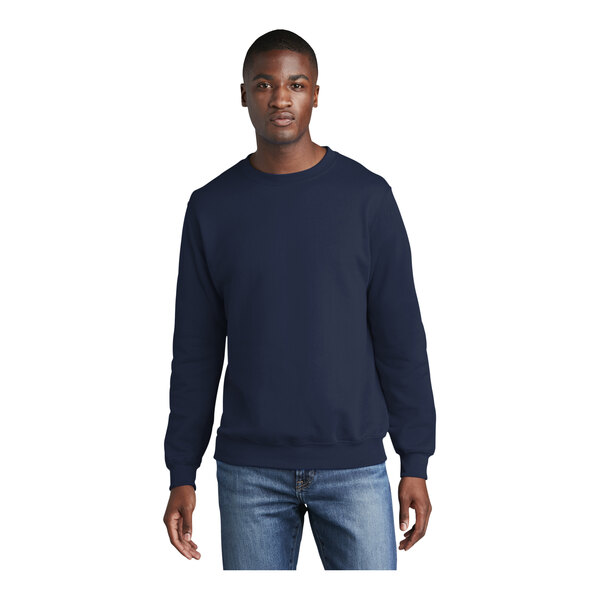 A man wearing a navy Port & Company fleece crewneck sweatshirt.