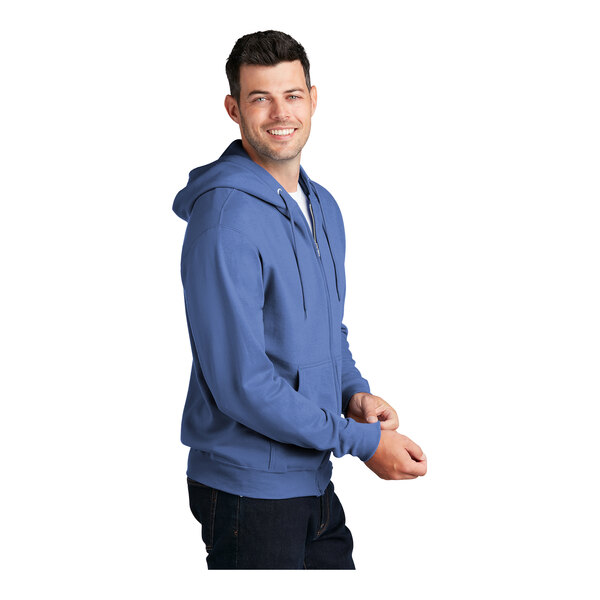 A man wearing a Carolina blue Port & Company full-zip hoodie.