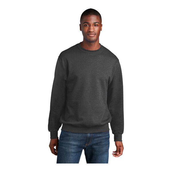 A man wearing a dark heather gray Port & Company core fleece crewneck sweatshirt.