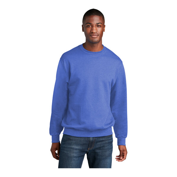 A man wearing a heather blue Port & Company fleece crewneck sweatshirt.