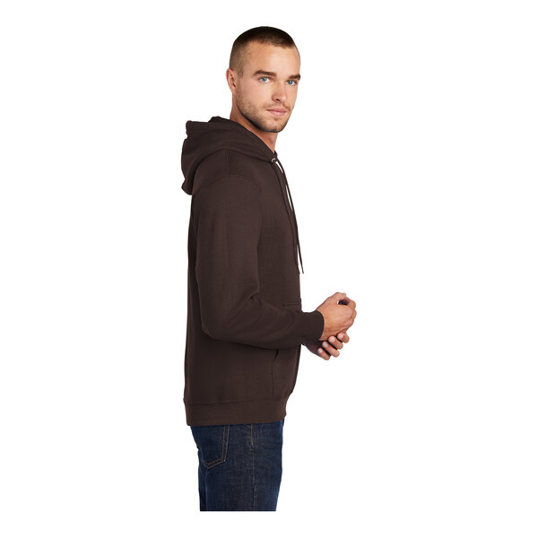 A person wearing a dark chocolate brown Port & Company fleece pullover hoodie.