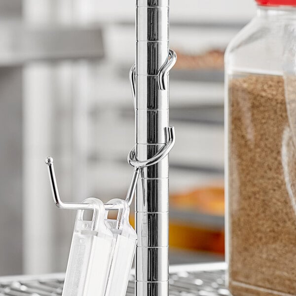 A Regency chrome utility hanger hooked to a metal pole.