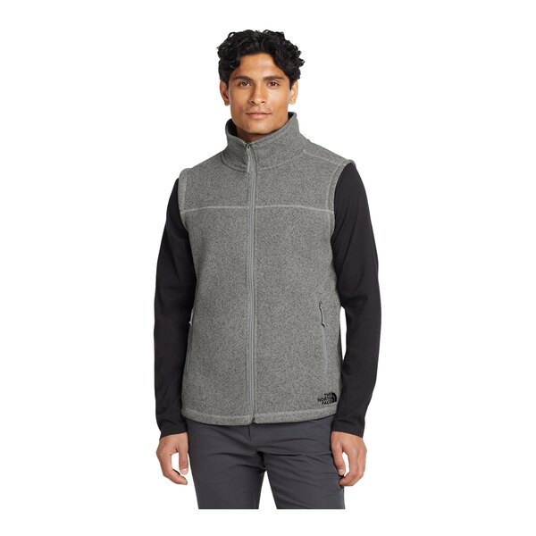 A man wearing a medium gray The North Face sweater vest.