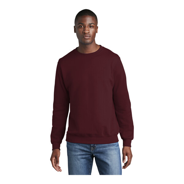 A man wearing a maroon Port & Company fleece crewneck sweatshirt.