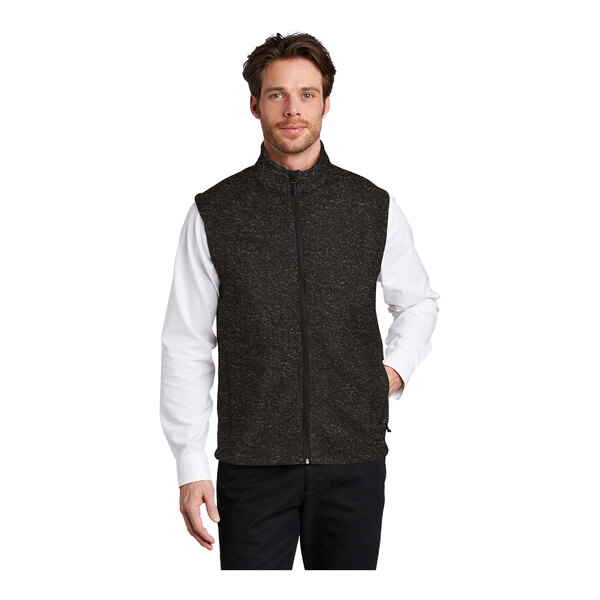 A man wearing a black heather fleece sweater vest with a zipper closure.