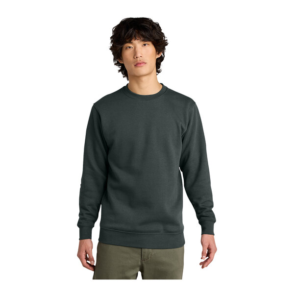A man wearing a charcoal District crewneck sweatshirt over a long sleeved shirt.