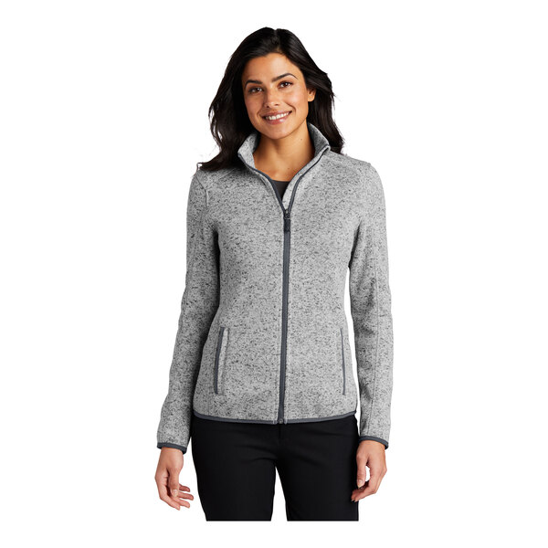 A woman wearing a gray Port Authority fleece sweater jacket with a full-zip.