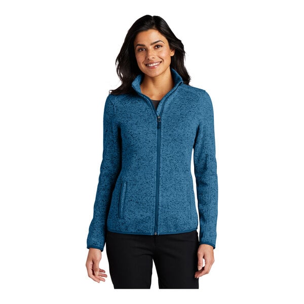A woman wearing a Port Authority blue heather fleece sweater jacket with a full-zip.