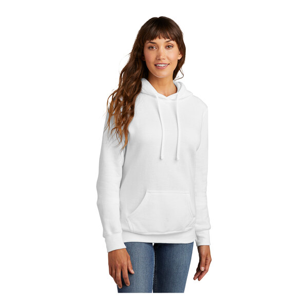 A woman wearing a white Port & Company pullover hoodie sweatshirt.