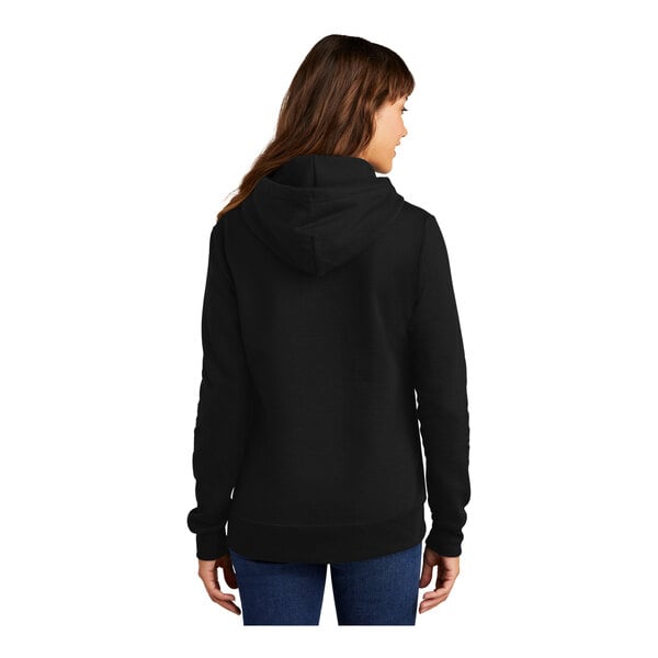 A woman wearing a black Port & Company Core Fleece pullover hoodie.