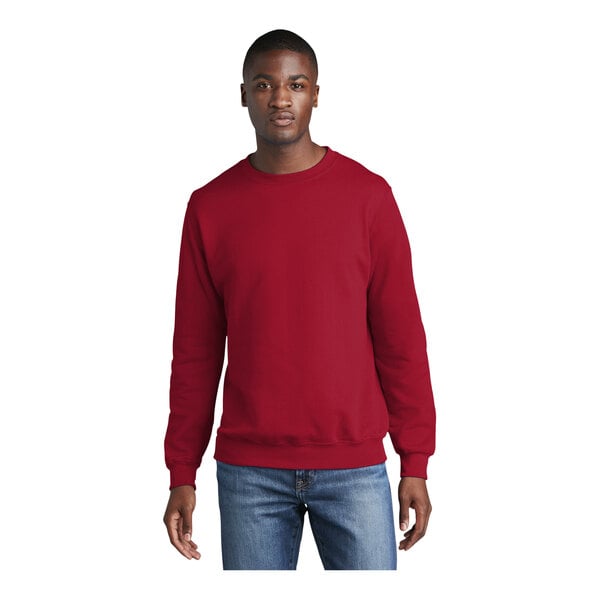A man wearing a red Port & Company crewneck sweatshirt.