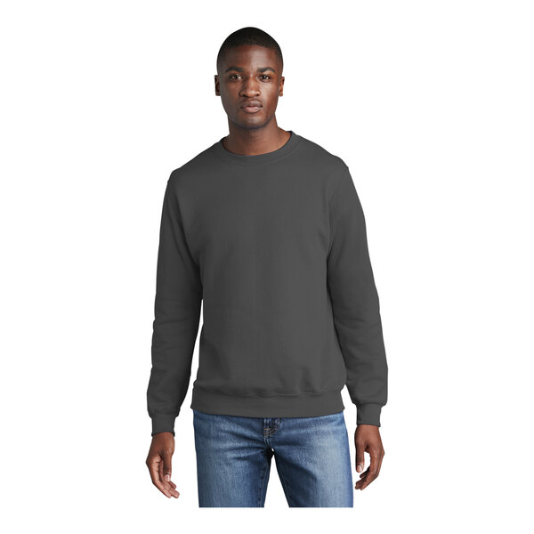 A man wearing a Port & Company charcoal core fleece crewneck sweatshirt.