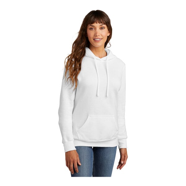 A woman wearing a Port & Company white core fleece pullover hoodie.