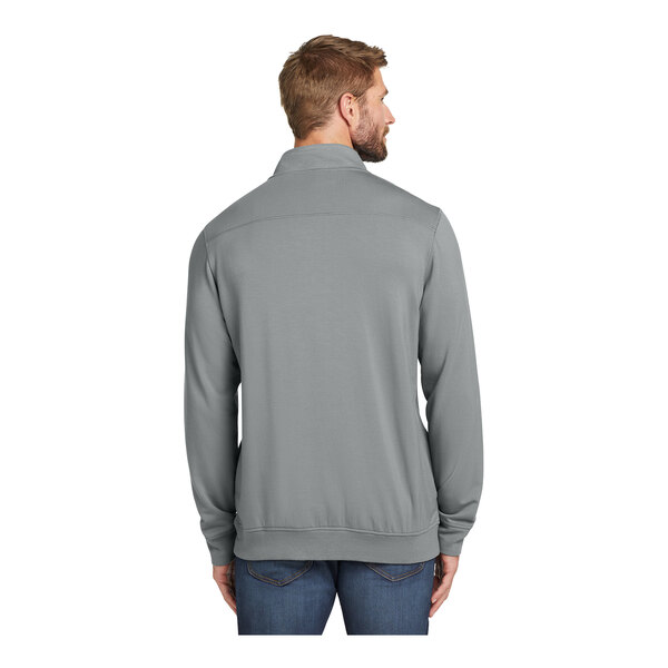 A man wearing a TravisMathew grey quarter-zip pullover.