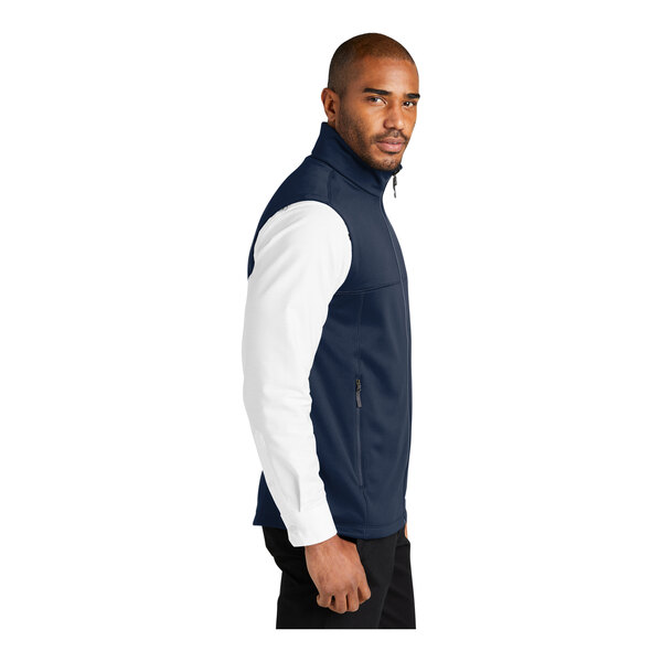 A person wearing a navy Port Authority fleece vest.