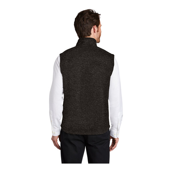 A man wearing a black heather Port Authority fleece sweater vest with a zipper closure.