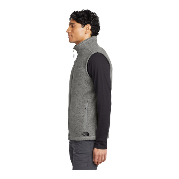 A person wearing a medium gray The North Face sweater vest.