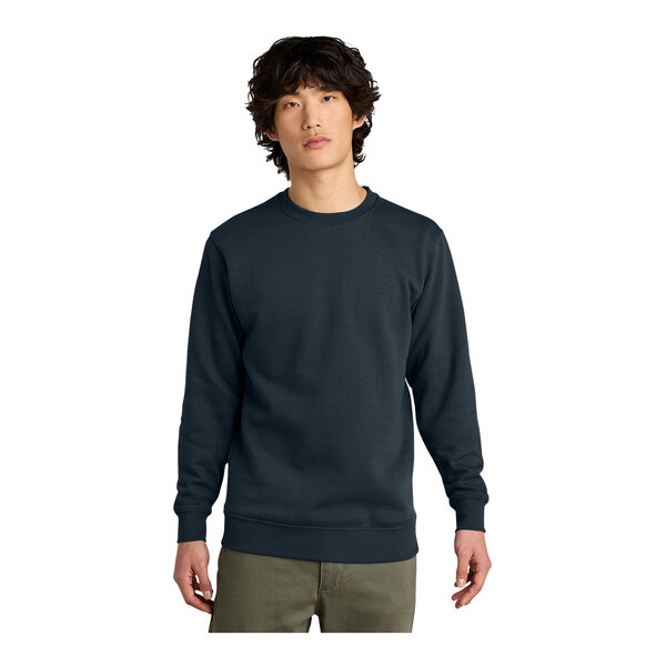 A man wearing a navy District fleece crewneck sweatshirt over a black shirt.