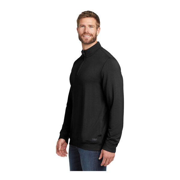 A man wearing a black TravisMathew Newport quarter-zip pullover.
