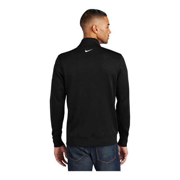 A man wearing a black Nike Dri-FIT half-zip sweater with a white swoosh on the back.