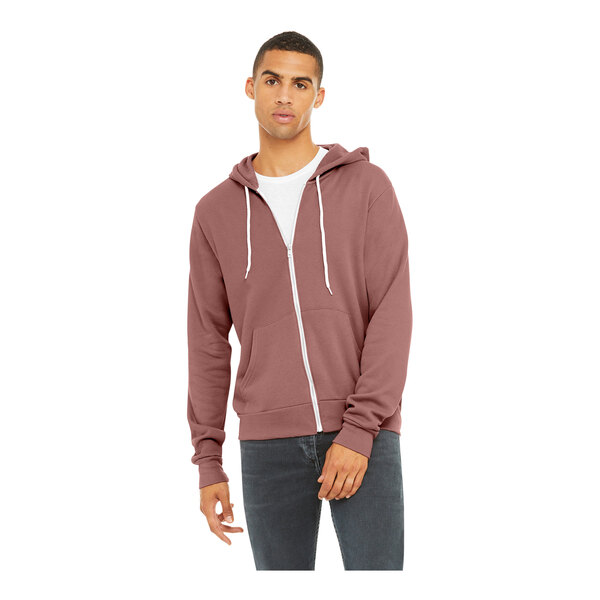 A person wearing a mauve Bella + Canvas zip-up hoodie.