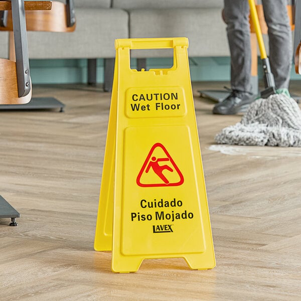 A yellow Lavex "CAUTION Wet Floor" sign on a wood floor.