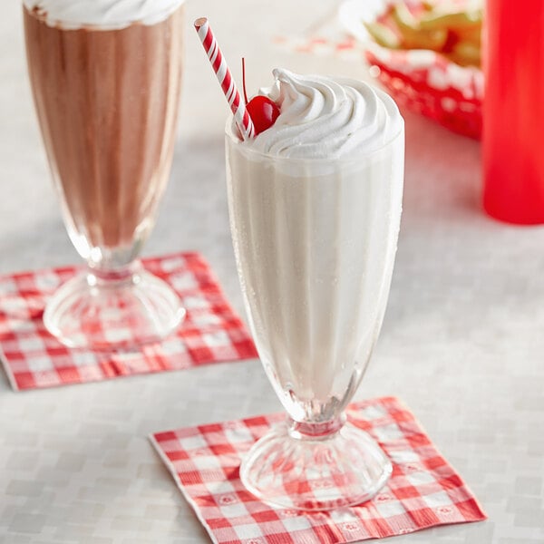 Two Acopa soda glasses filled with milkshakes topped with whipped cream and cherries.