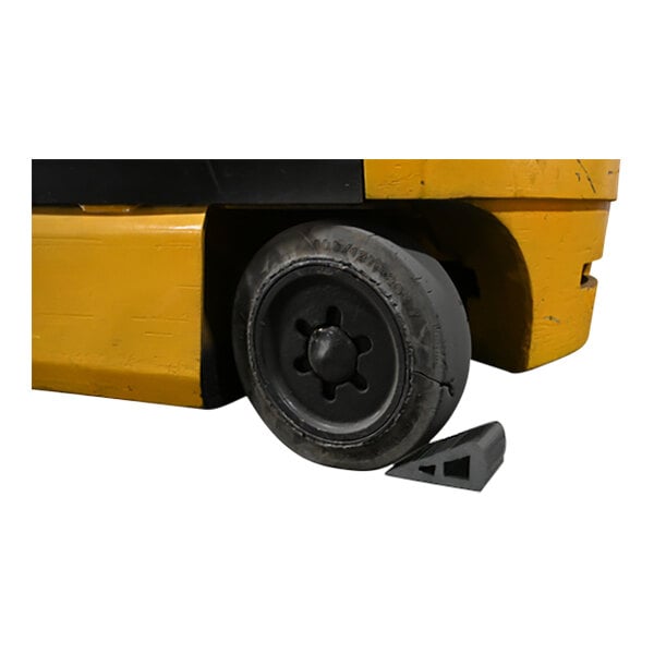 A forklift tire secured with a black rubber triangular wedge.