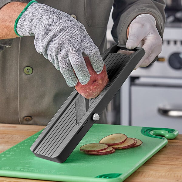 A person using Emperor's Select small plastic mandoline to cut potatoes.