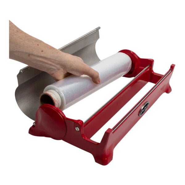 A hand using a Boska red foil dispenser to hold a roll of plastic film.