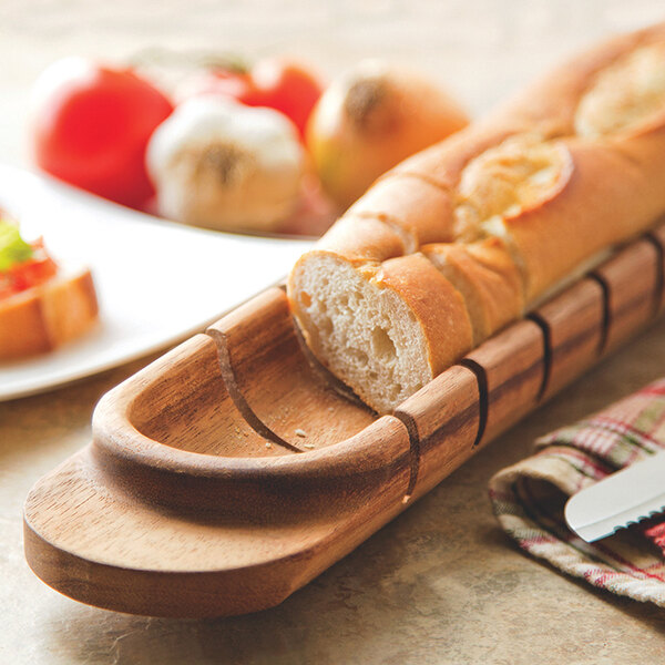 An Ironwood acacia wood baguette miter holding a loaf of bread.