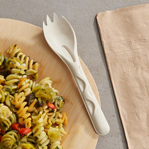 A plate of pasta with a World Centric compostable fiber spork on a table.