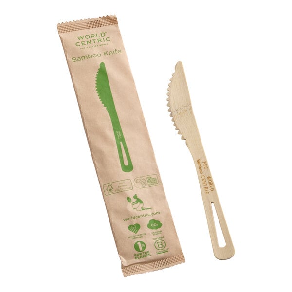 A compostable bamboo knife with a serrated edge, shown next to its eco-friendly paper packaging.